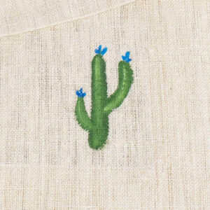Piccolo cactus con fiori blu alle estremità, ricamato su una tovaglia in fibra di canapa