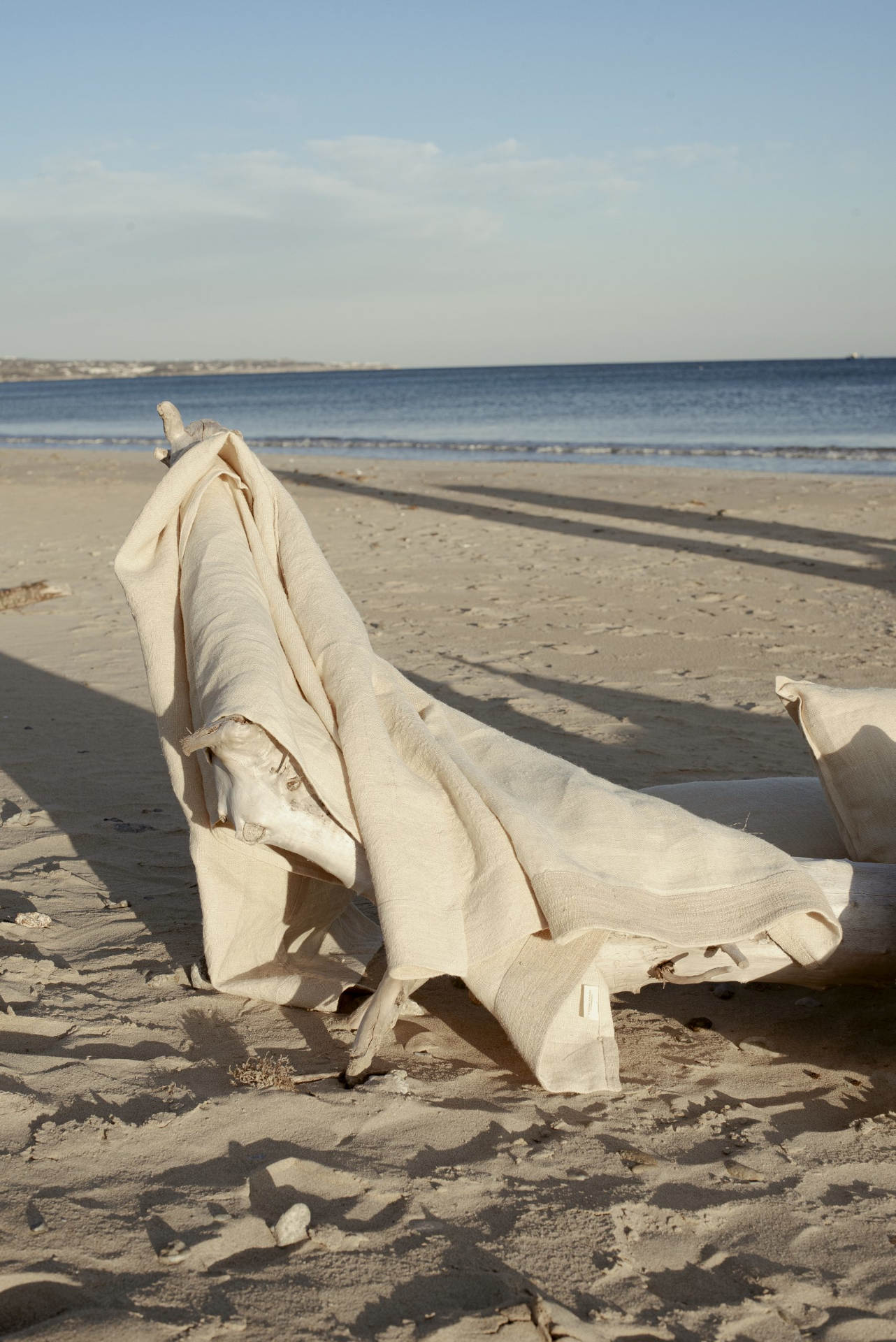 Tronco marino in spiaggia coperto da un telo tessicanapa beige
